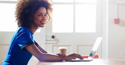 young-woman-in-blue-dress-typing-on-laptop