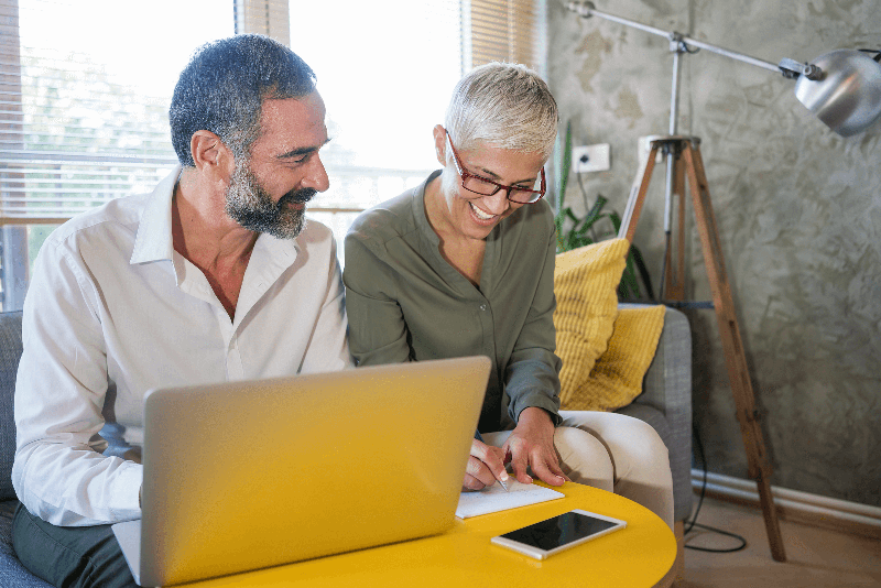 man and woman working on electronic paperwork on laptop